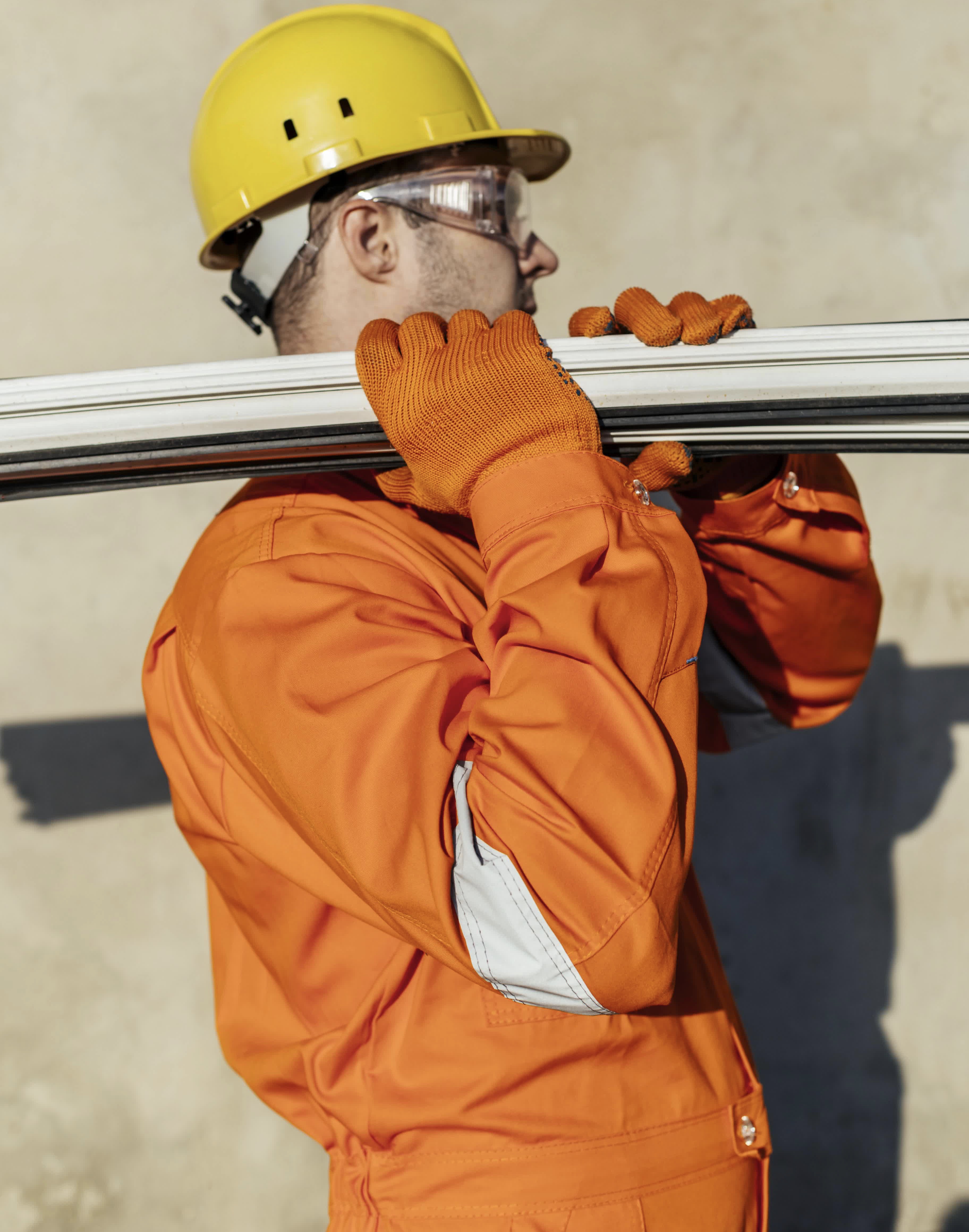 side view-of-male-laborer-with-hard-hat-carrying-steel